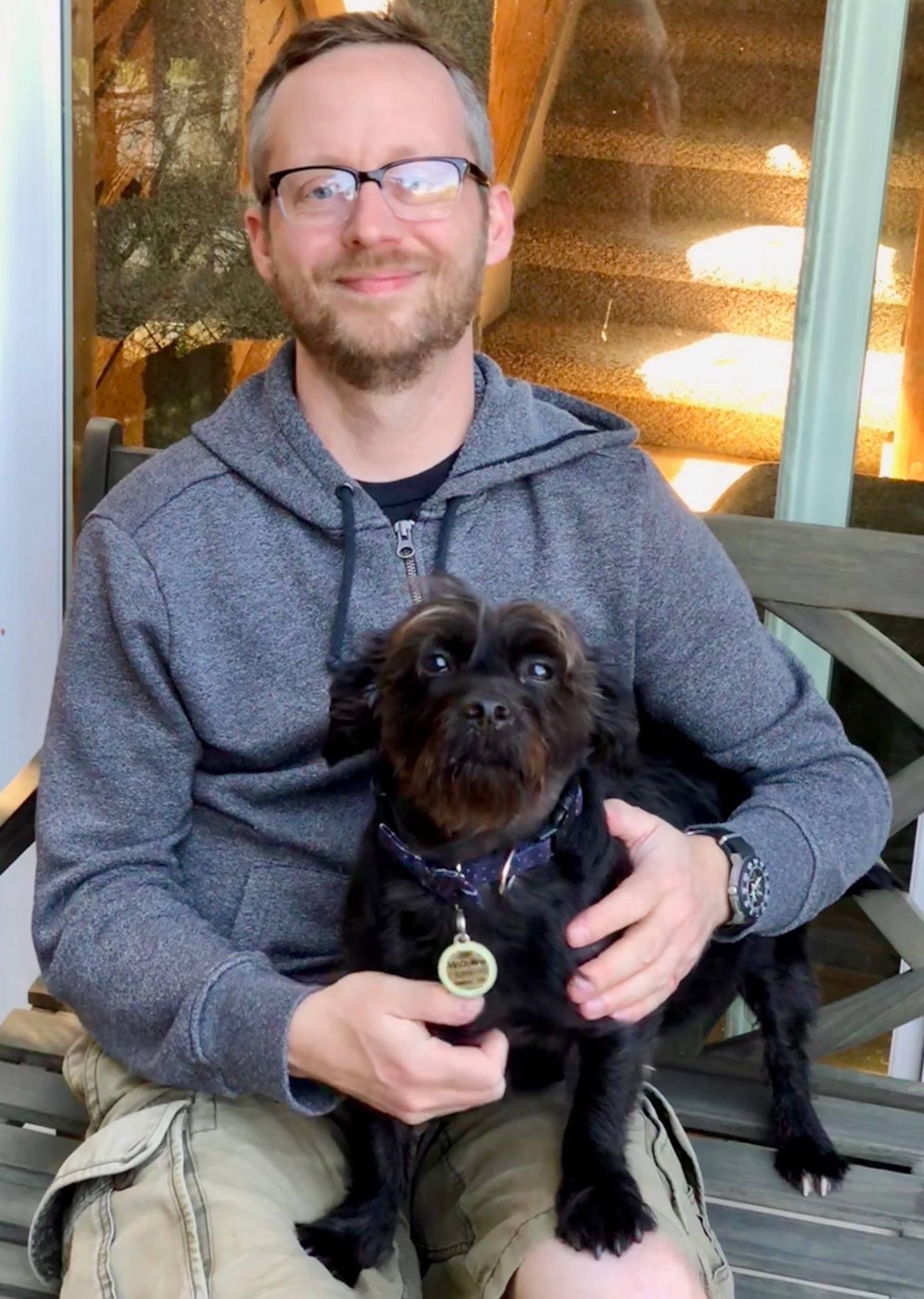 Sean McQuilling seated outdoors with his rescue dog Jax